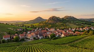 Vue aérienne de Kretz, Allemagne, avec ses maisons aux toits rouges, ses vignobles luxuriants et collines au coucher du soleil.