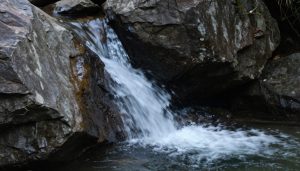 Une petite cascade coulant entre de grands rochers sombres en Corse.