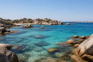 Vue sur une crique aux eaux turquoise entourée de rochers granitiques aux îles Lavezzi, en Corse.