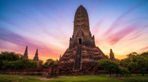Temple de Wat Chaiwatthanaram, Ayutthaya, Thaïlande, au coucher du soleil. Architecture khmère en brique sous un ciel vibrant de rose et bleu.